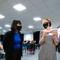 Scholar wearing mask presenting poster to three guests wearing masks.